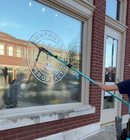 Commercial window cleaner using a water-fed pole on a storefront window